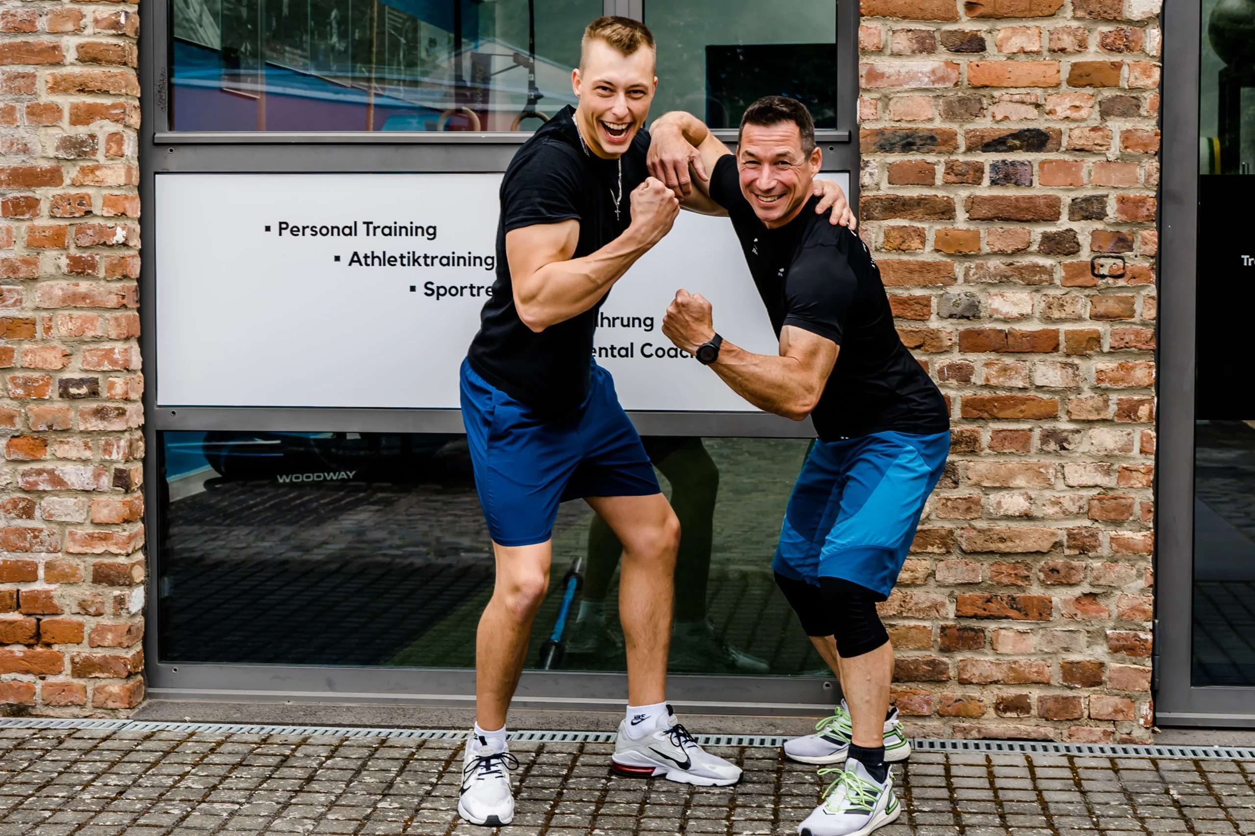 Sowohl der Personal Trainer als auch der Trainierende spannen Ihre Armmuskeln an